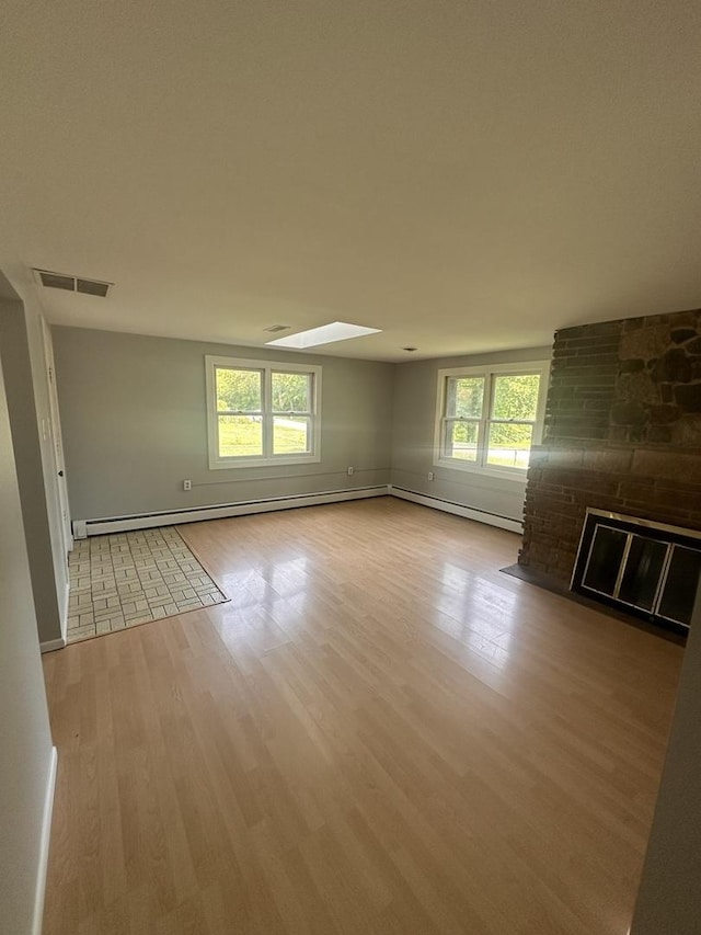 empty room featuring a baseboard radiator, a large fireplace, and light hardwood / wood-style flooring