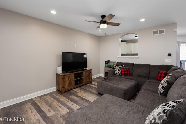 living room featuring ceiling fan and dark hardwood / wood-style floors