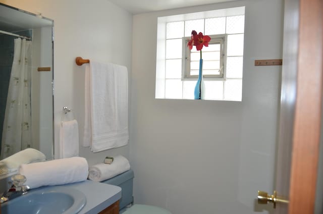 bathroom featuring walk in shower, vanity, and toilet