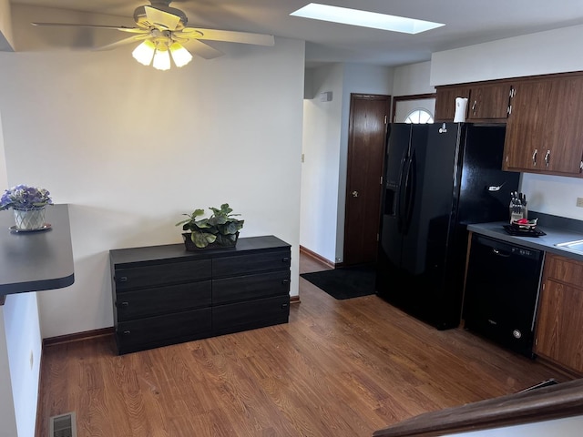 kitchen featuring dark hardwood / wood-style floors, a skylight, black appliances, ceiling fan, and dark brown cabinetry