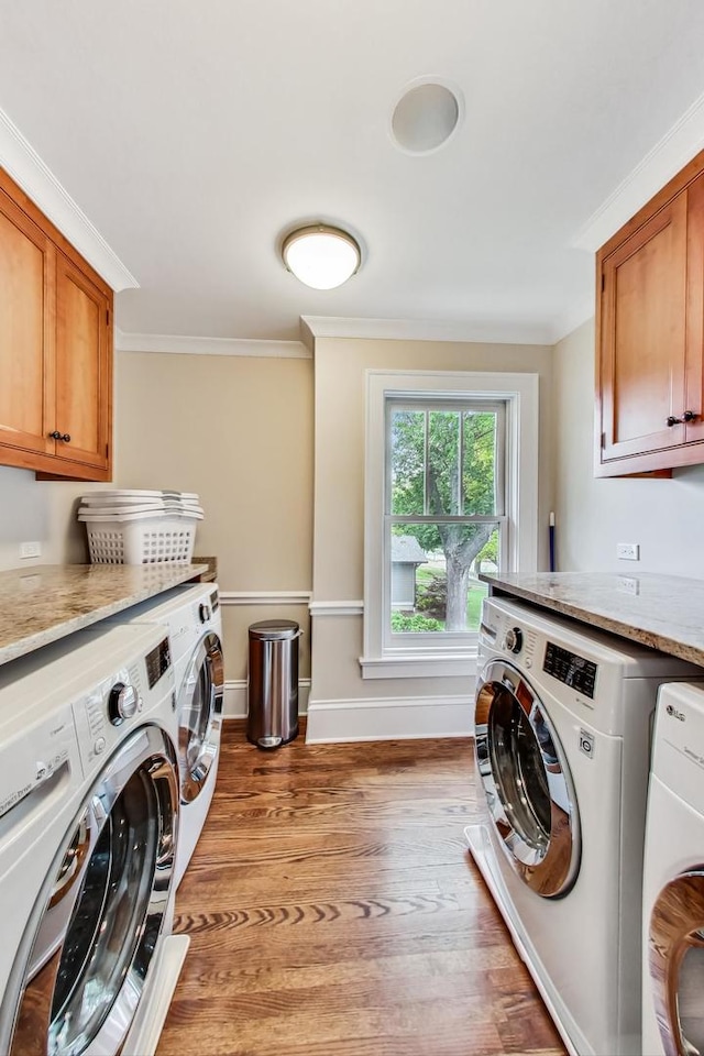 clothes washing area featuring light wood-type flooring, washing machine and dryer, ornamental molding, and cabinets