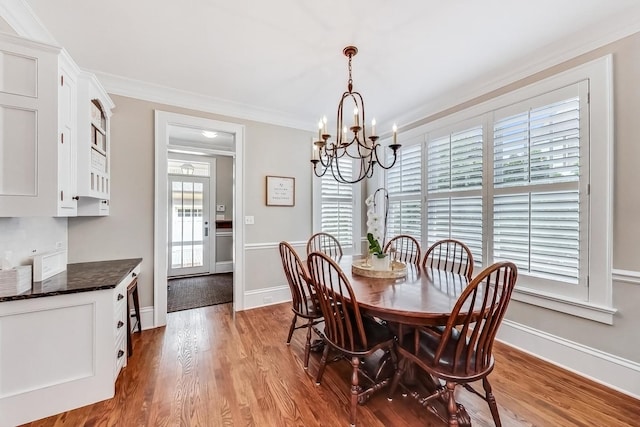 dining area with a chandelier, ornamental molding, and hardwood / wood-style flooring