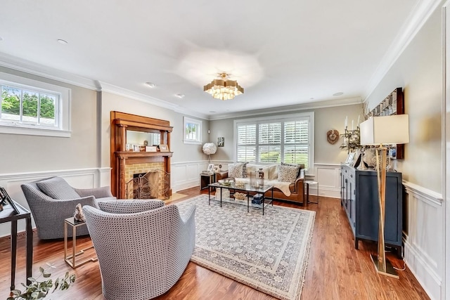 living room with a brick fireplace, a chandelier, crown molding, and light hardwood / wood-style floors