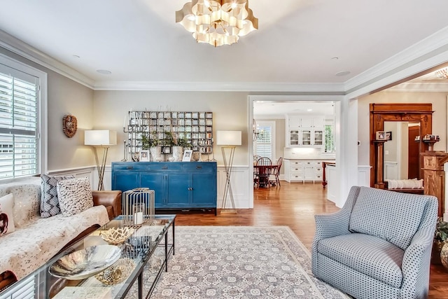 living room with plenty of natural light, ornamental molding, and a notable chandelier