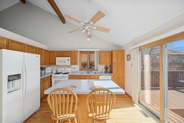 kitchen with a kitchen bar, sink, a center island, white appliances, and light hardwood / wood-style floors