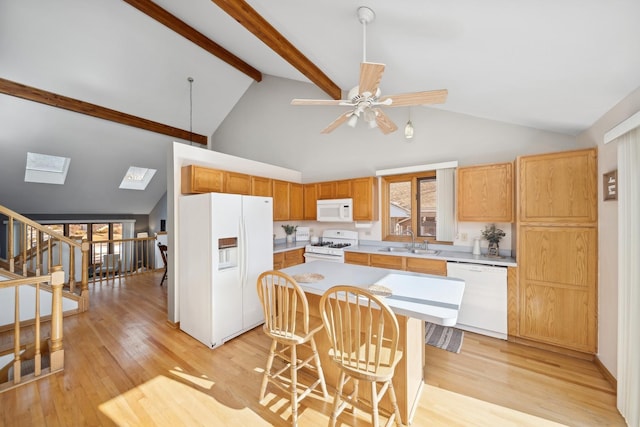 kitchen with a breakfast bar, sink, a kitchen island, white appliances, and light hardwood / wood-style floors