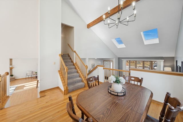 dining room with a chandelier, a skylight, high vaulted ceiling, light hardwood / wood-style flooring, and beamed ceiling