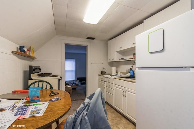 kitchen featuring vaulted ceiling, white cabinetry, sink, and white appliances