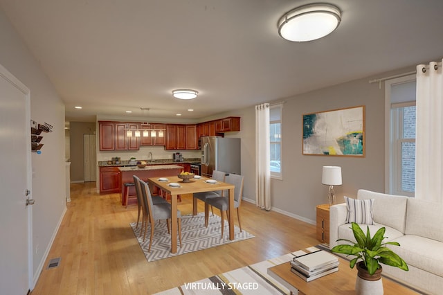 kitchen featuring stainless steel fridge with ice dispenser, plenty of natural light, light hardwood / wood-style flooring, and hanging light fixtures