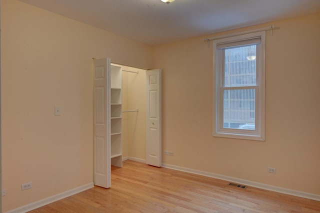 unfurnished bedroom with multiple windows, a closet, and light wood-type flooring