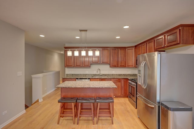 kitchen with a center island, stainless steel appliances, sink, a kitchen breakfast bar, and hanging light fixtures