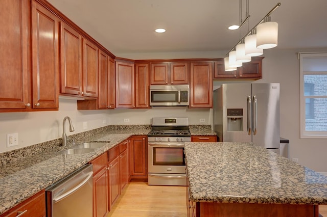 kitchen featuring stone counters, appliances with stainless steel finishes, a kitchen island, and sink