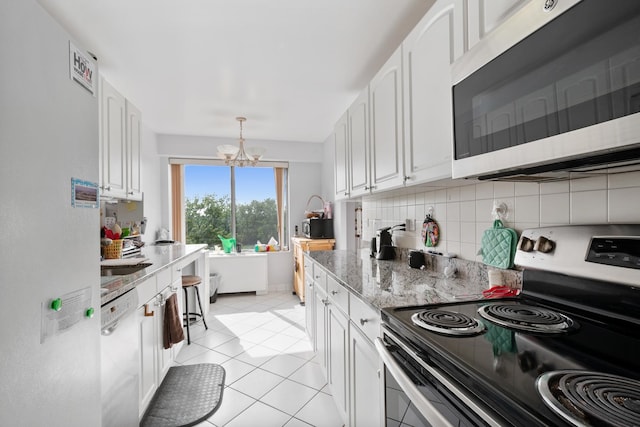 kitchen with backsplash, stainless steel appliances, white cabinets, light stone counters, and a chandelier