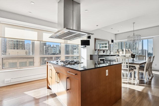 kitchen featuring a center island, hanging light fixtures, light wood-type flooring, island exhaust hood, and stainless steel gas stovetop