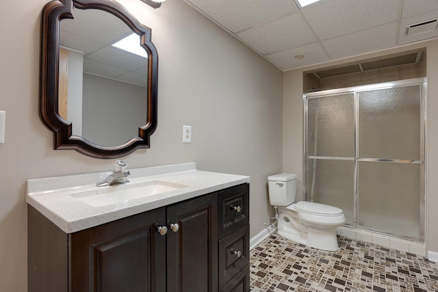 bathroom with vanity, toilet, a shower with door, and a drop ceiling