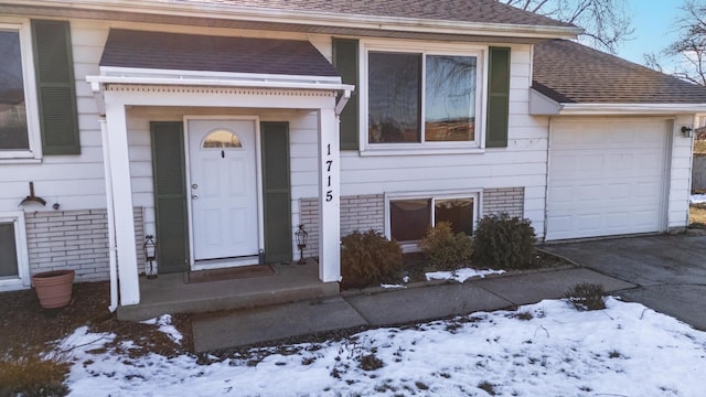 snow covered property entrance featuring a garage