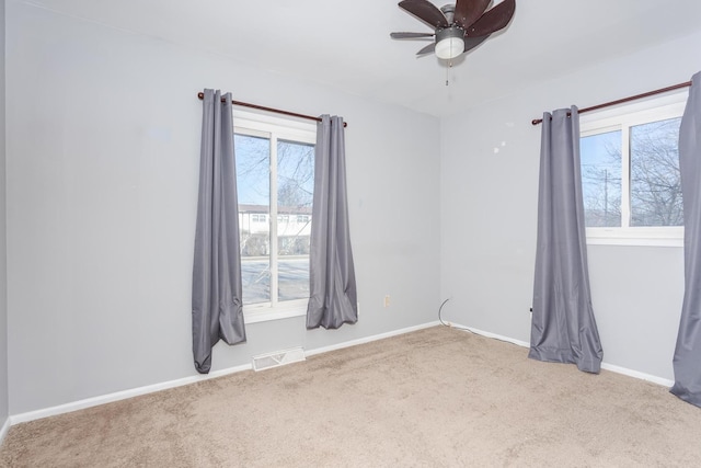 empty room with ceiling fan, plenty of natural light, and carpet