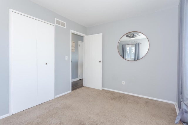 unfurnished bedroom featuring light carpet and a closet