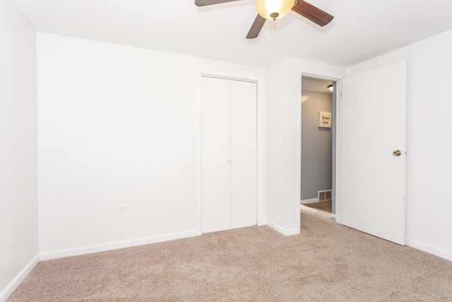 unfurnished bedroom with ceiling fan, a closet, and light colored carpet