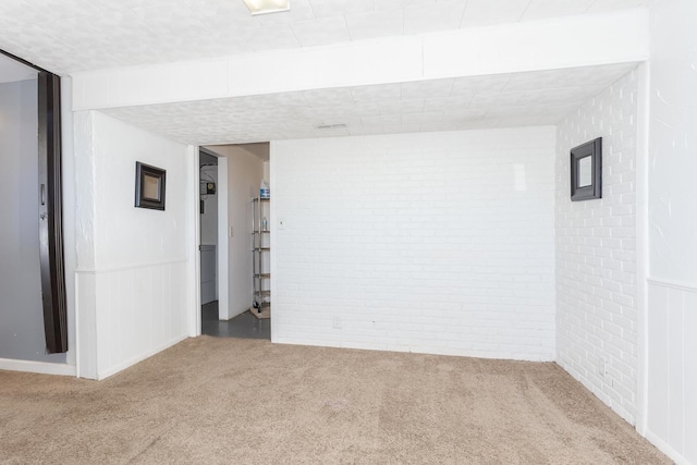 empty room featuring brick wall and carpet flooring