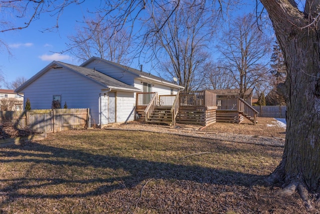 rear view of house featuring a wooden deck and a yard