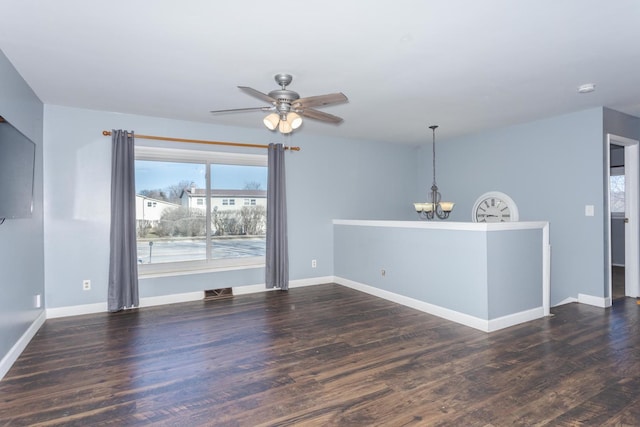 empty room with dark hardwood / wood-style flooring and ceiling fan with notable chandelier