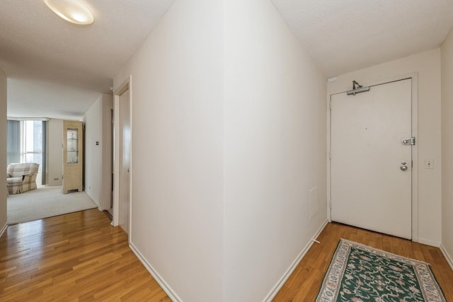 hallway featuring light wood-type flooring and a textured ceiling