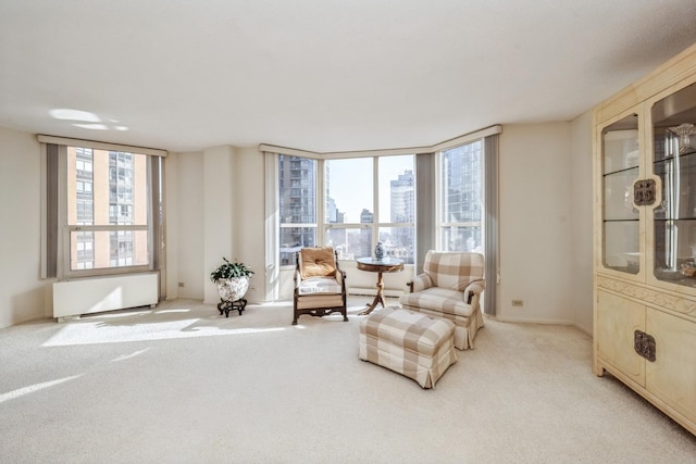 sitting room with a healthy amount of sunlight, radiator, and light carpet