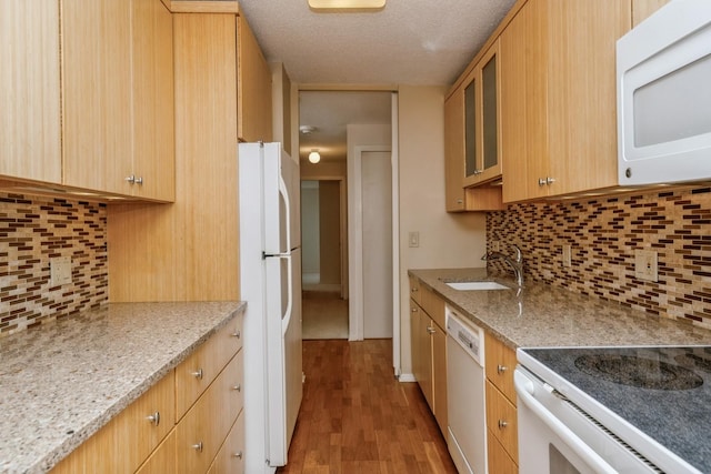 kitchen with sink, backsplash, white appliances, and light stone counters