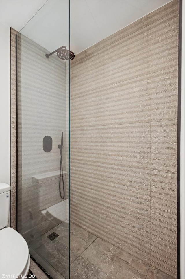 bathroom with tiled shower and toilet