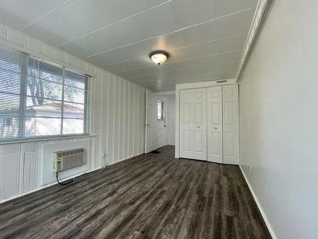 unfurnished bedroom with dark wood-type flooring, a closet, and a wall mounted air conditioner