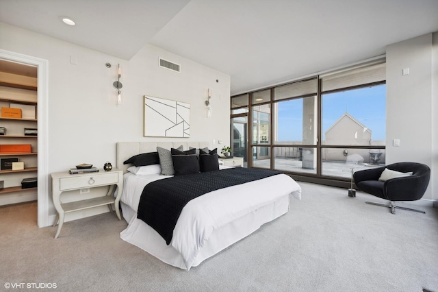 bedroom with carpet floors, expansive windows, and a walk in closet