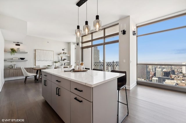 kitchen featuring decorative light fixtures, light stone countertops, dark hardwood / wood-style floors, and a kitchen island