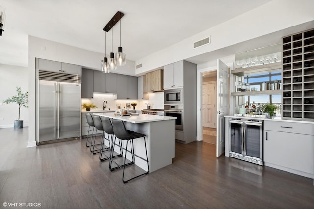 kitchen with pendant lighting, a kitchen island, built in appliances, wine cooler, and decorative backsplash