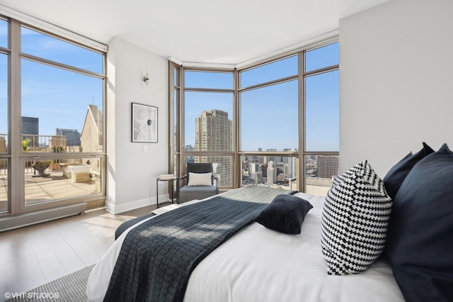 bedroom featuring light wood-type flooring, floor to ceiling windows, and multiple windows