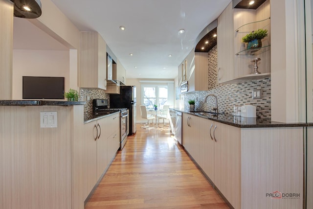 kitchen with sink, dark stone countertops, light hardwood / wood-style floors, stainless steel appliances, and light brown cabinets