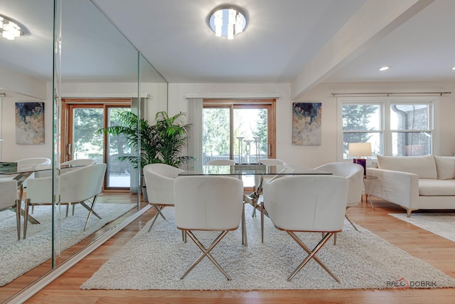 dining area with beam ceiling and light hardwood / wood-style flooring