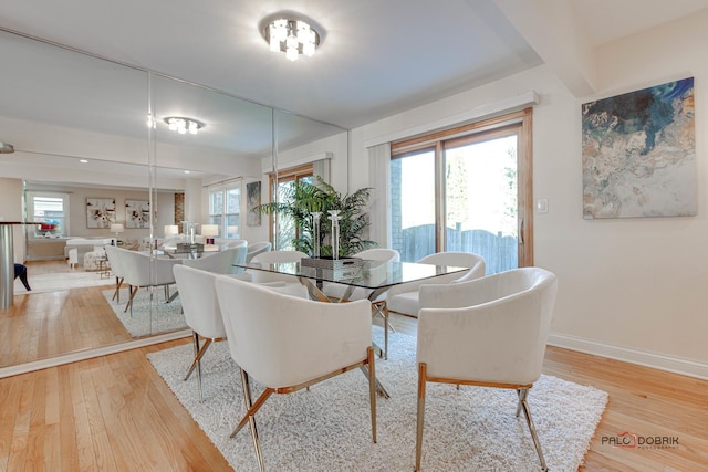 dining area with beamed ceiling and light hardwood / wood-style floors