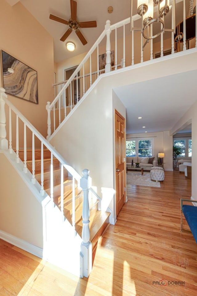 stairs with ceiling fan with notable chandelier and hardwood / wood-style floors