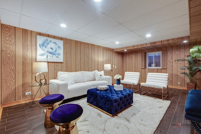 living room with a paneled ceiling and wood walls