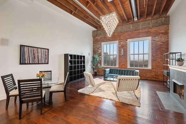 living room with wood ceiling, beam ceiling, a high ceiling, brick wall, and dark hardwood / wood-style flooring