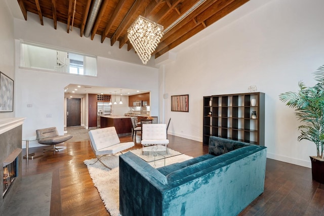 living room with an inviting chandelier, a towering ceiling, beamed ceiling, and hardwood / wood-style flooring