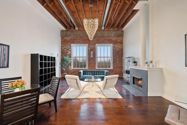 living area with beamed ceiling, dark hardwood / wood-style floors, a high ceiling, and brick wall