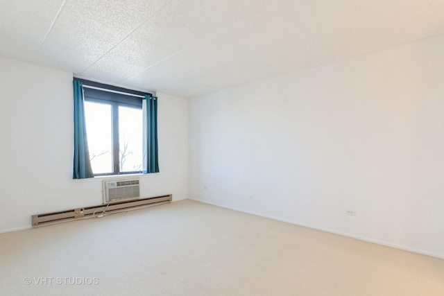 carpeted spare room featuring a wall unit AC, a textured ceiling, and baseboard heating