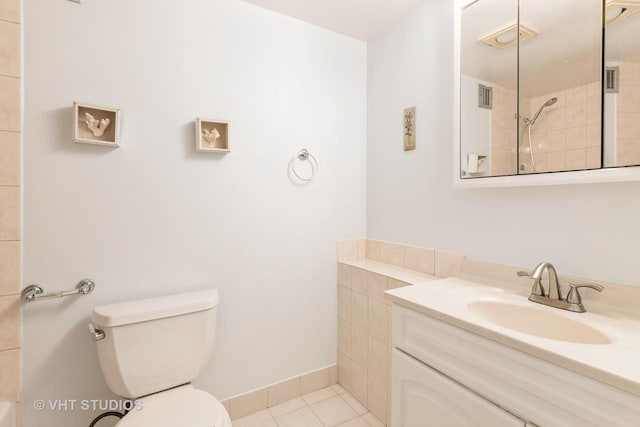 bathroom with vanity, tile patterned floors, toilet, and a tile shower