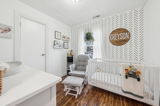 bedroom with dark hardwood / wood-style floors and a nursery area