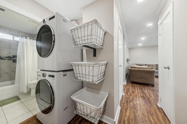 clothes washing area featuring stacked washer / drying machine and hardwood / wood-style floors