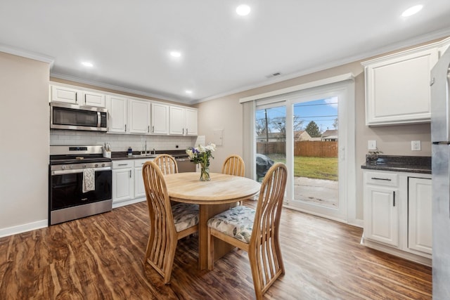 kitchen featuring appliances with stainless steel finishes, crown molding, white cabinetry, and dark hardwood / wood-style floors