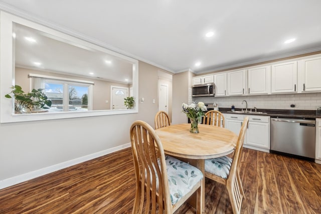 dining space featuring dark hardwood / wood-style flooring, ornamental molding, and sink