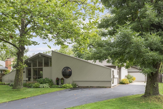 view of front of home featuring a garage, a sunroom, and a front lawn